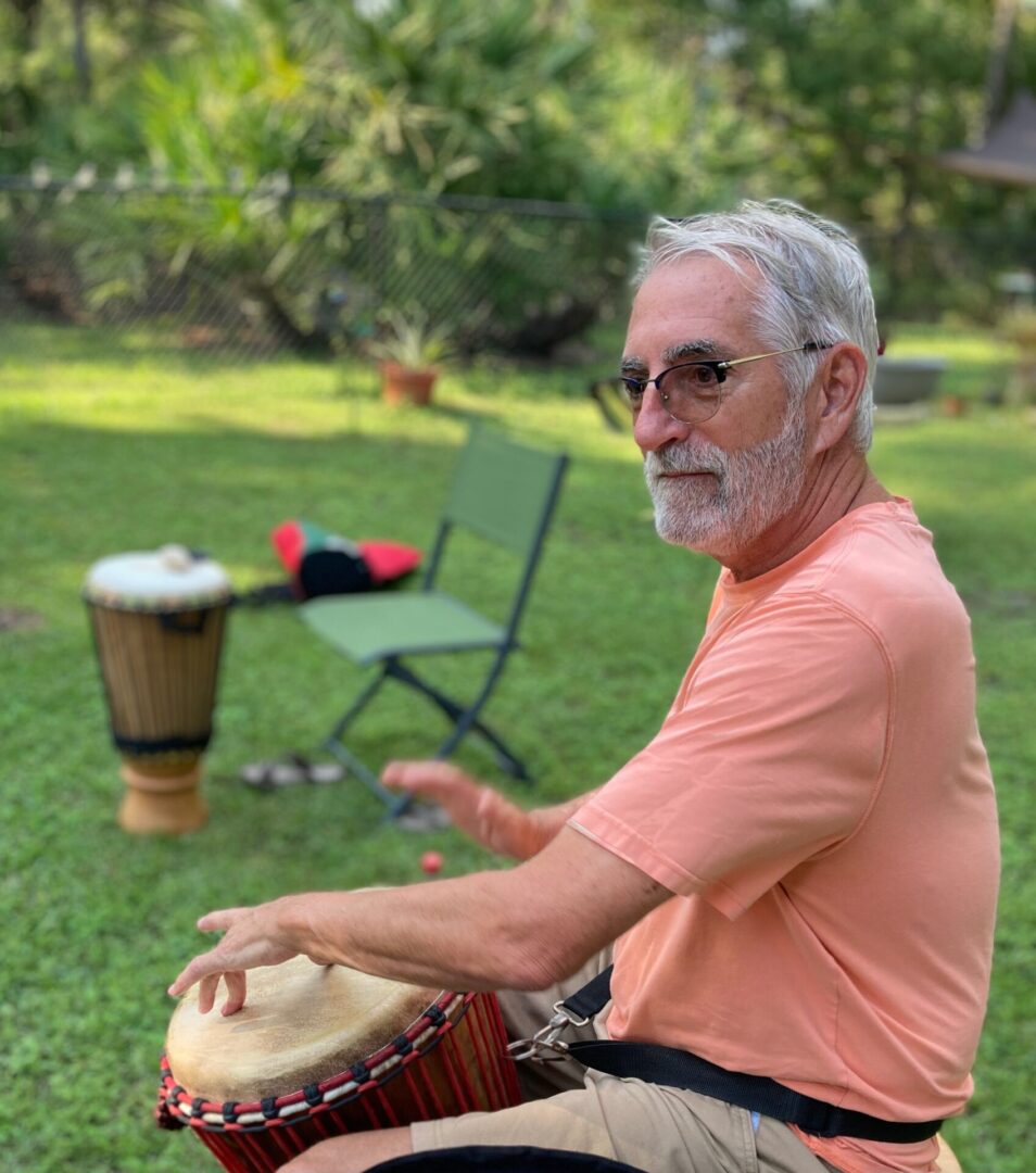 A man playing the drum in an outdoor setting.