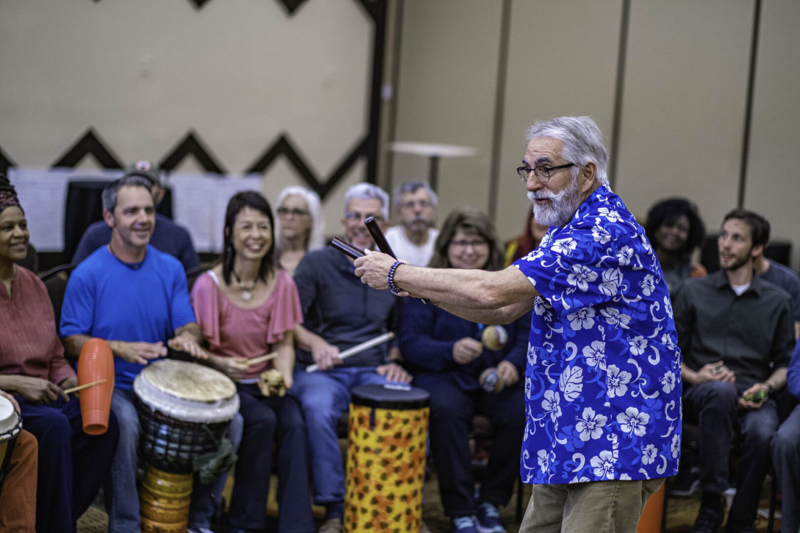 A man in blue shirt playing drum with people.